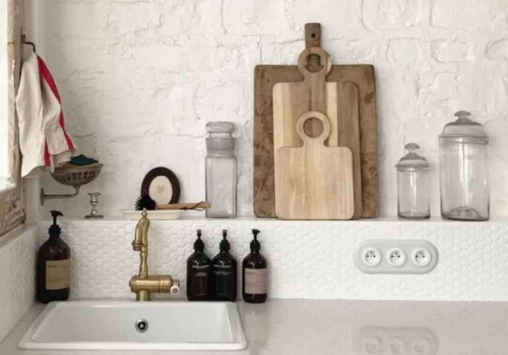Dans une cuisine en pierre et c�ramique blanches, au-dessus du plan de travail, se situe une plaque triple en porcelaine blanche avec prises de courant. 