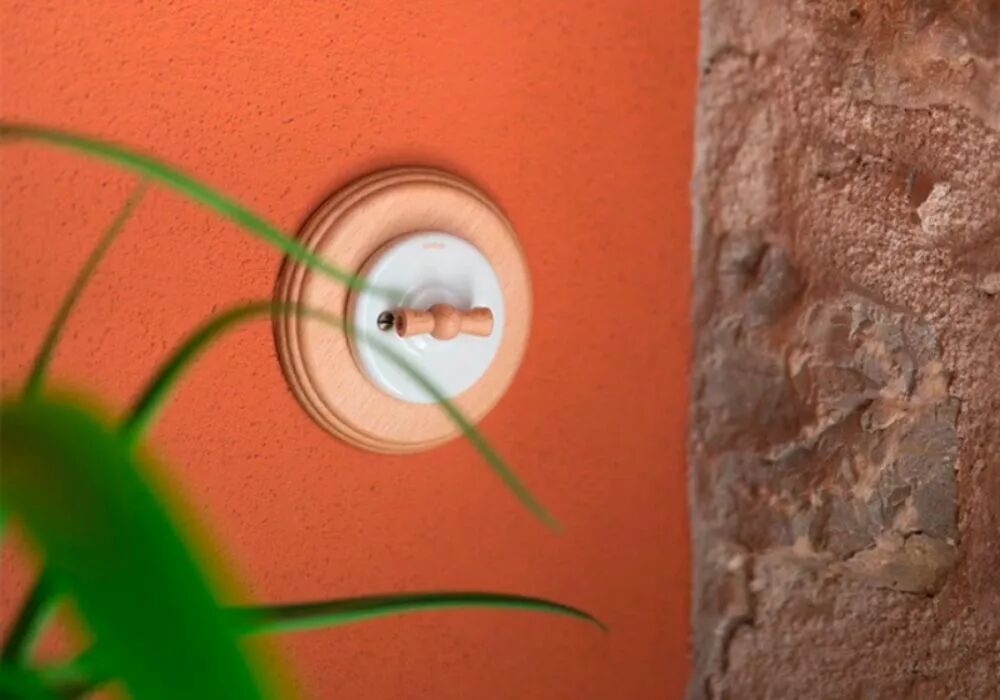 Sur un mur couleur argile se d�tache une plaque en h�tre Garby Colonial avec son interrupteur en porcelaine blanche. La manette rotative est �galement en bois.