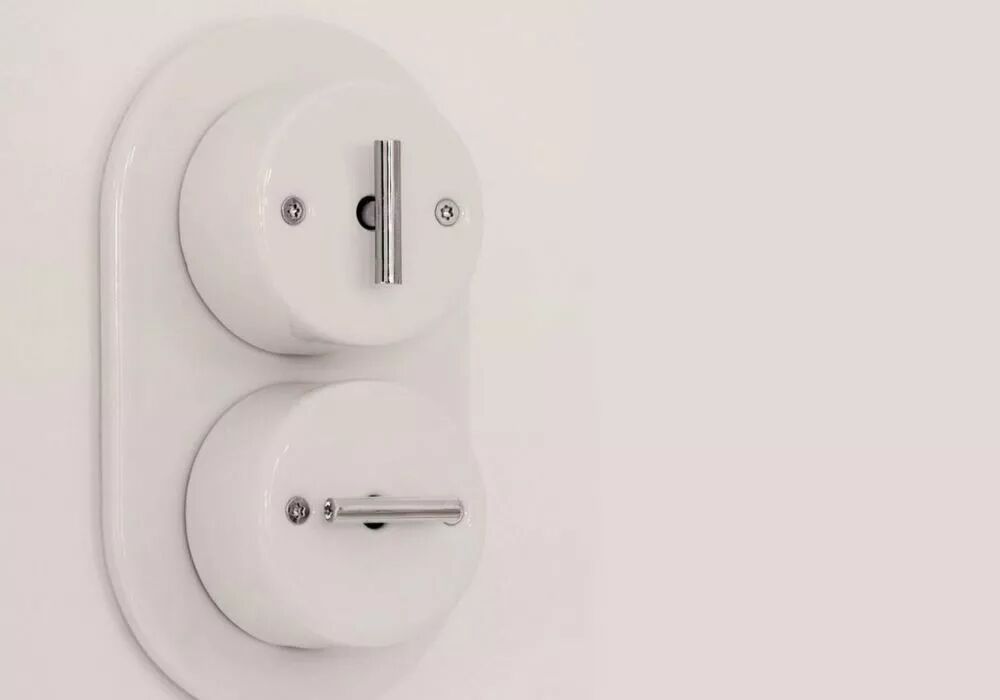 Sur un mur blanc avec plaque de finition double accueillant deux interrupteurs en porcelaine blanche et leviers chrom�s.